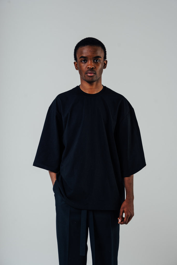 Relaxed cropped fit tee in black, made from cotton blend, modeled by a man wearing a size small.
