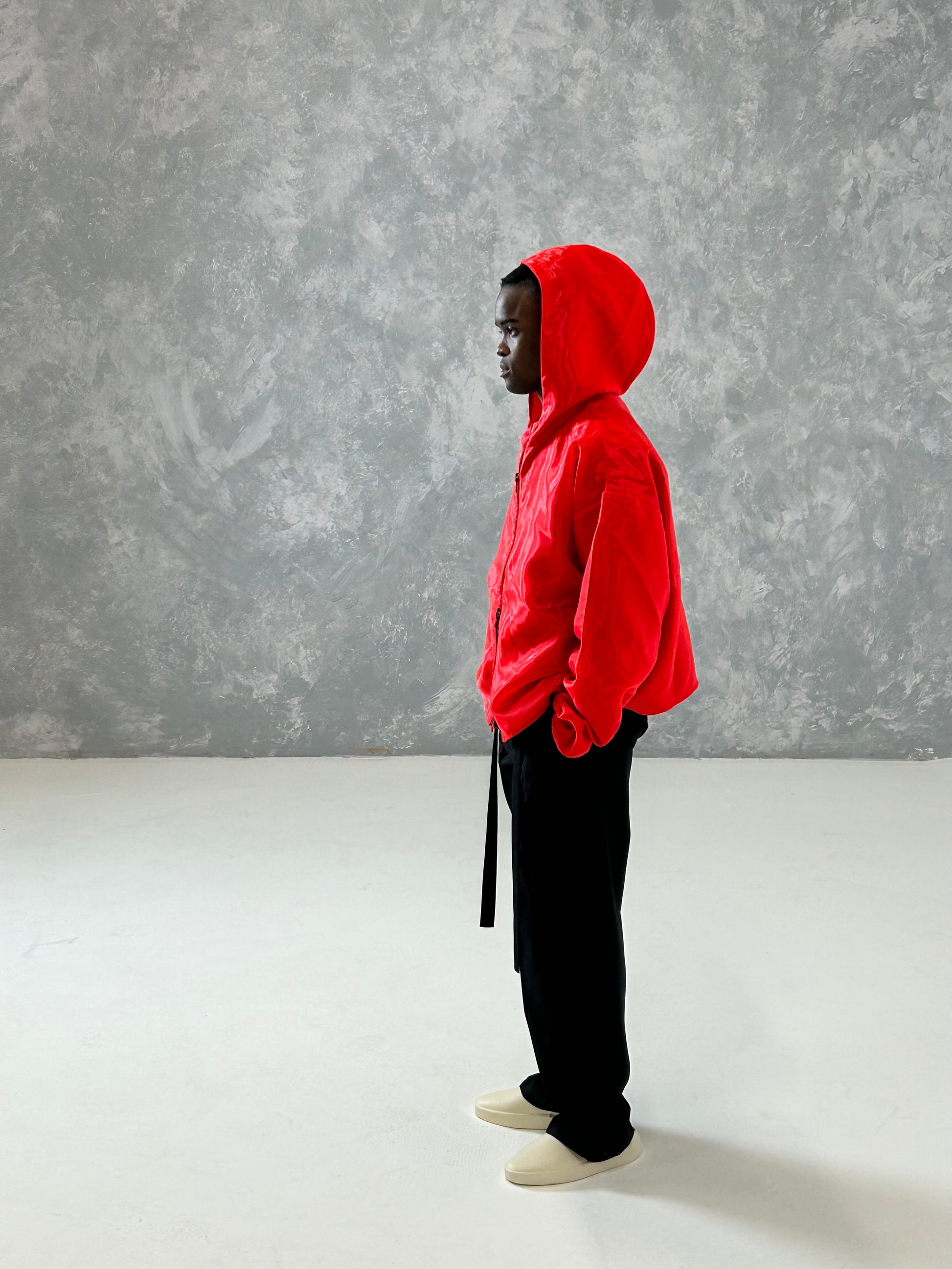 Profile view of model wearing flame red organza hooded zip jacket with boxy oversized fit and cropped body.