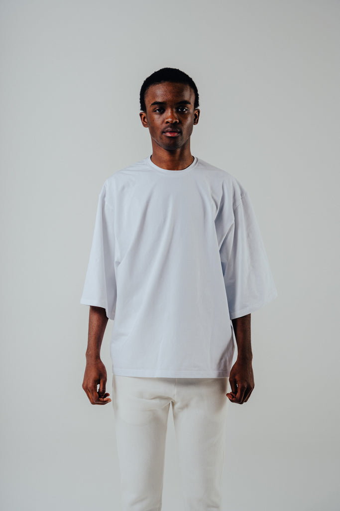 Relaxed cropped fit cotton tee in white worn by model, featuring slightly lengthened sleeves and soft cotton blend fabric.