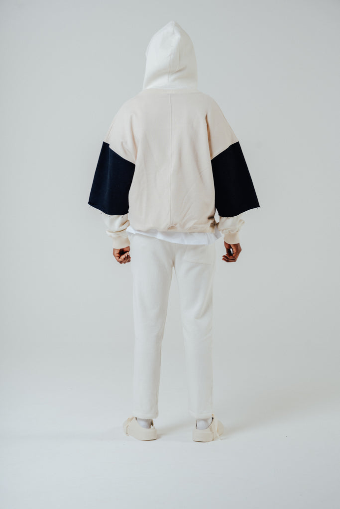 Back view of model wearing a cropped boxy fit Henley top in cream and black with matching sweatpants.