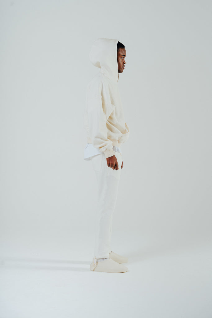 Side view of model in oversized boxy cream hoody, showcasing fleeceback cotton blend and relaxed fit style.