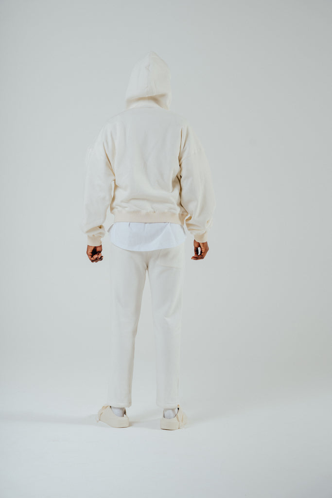 Model wearing relaxed fit fleeceback jogger in cream with a hooded sweatshirt, showcasing a casual back view.
