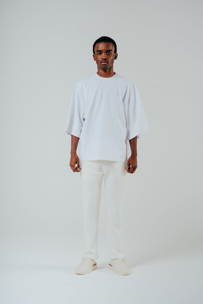 Model in relaxed cropped cotton tee in white, paired with white pants, showcasing a casual and comfortable style.