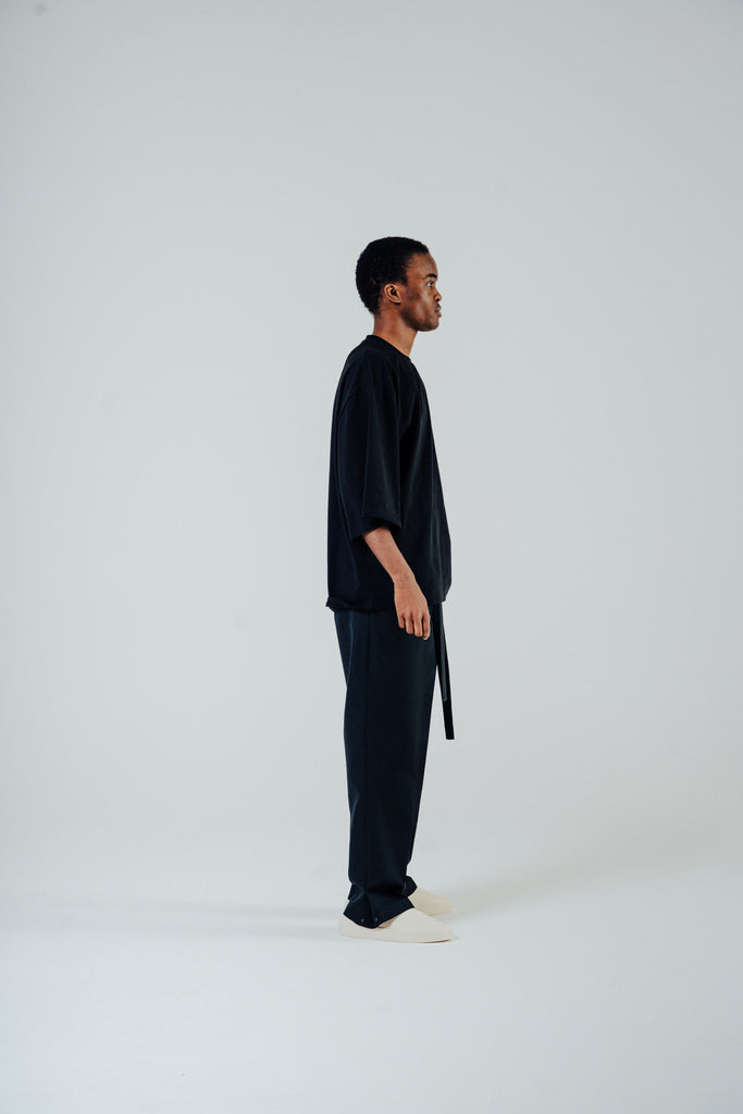 Model wearing tailored rope belt trousers in black, showcasing relaxed fit and unique design elements.