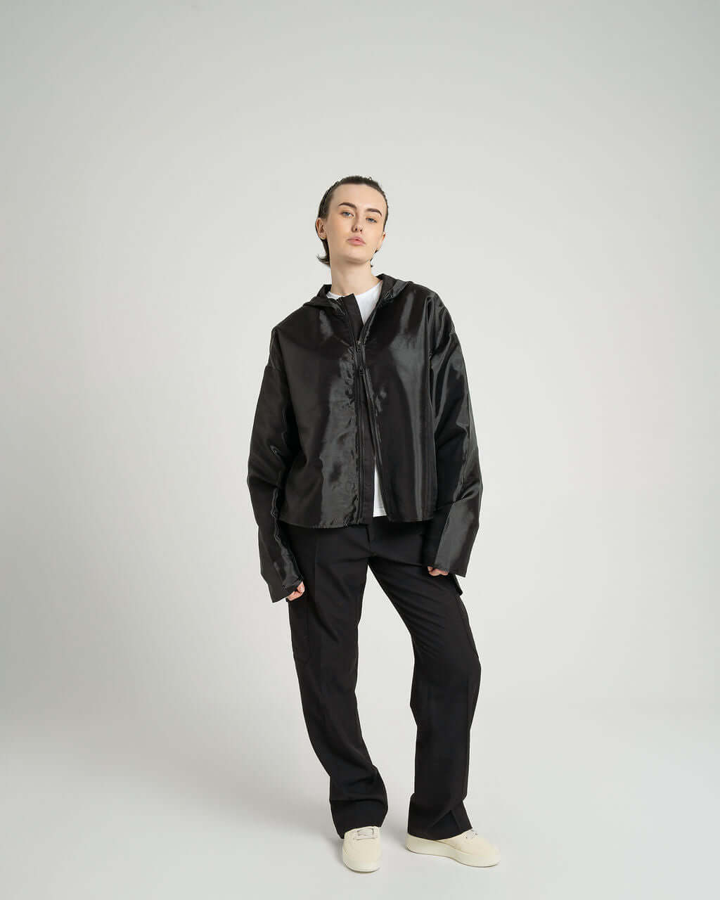Model wearing the 'Virgil' Organza hooded zip-up jacket in black, styled with loose-fit pants.