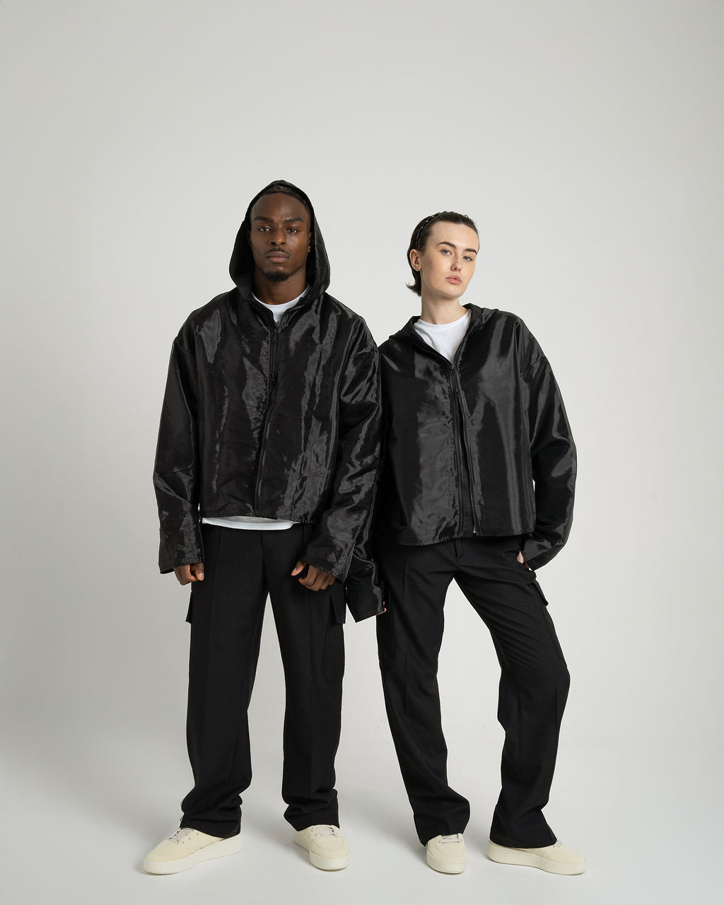 Two models wearing the 'Virgil' Organza hooded zip-up jacket in black, showcasing its oversized fit and stylish design.