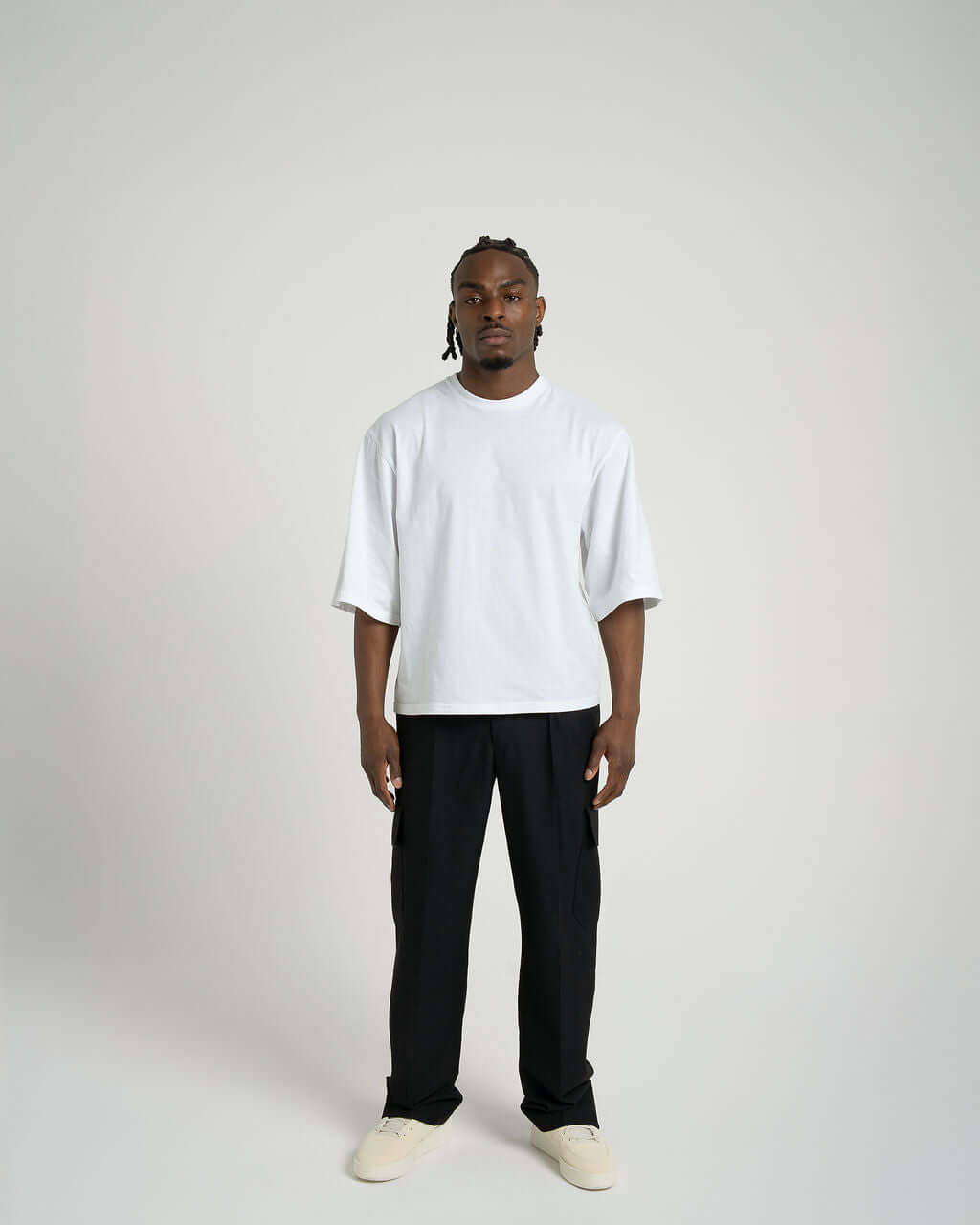 Man wearing a boxy cropped white cotton tee with relaxed fit and slightly lengthened sleeves.