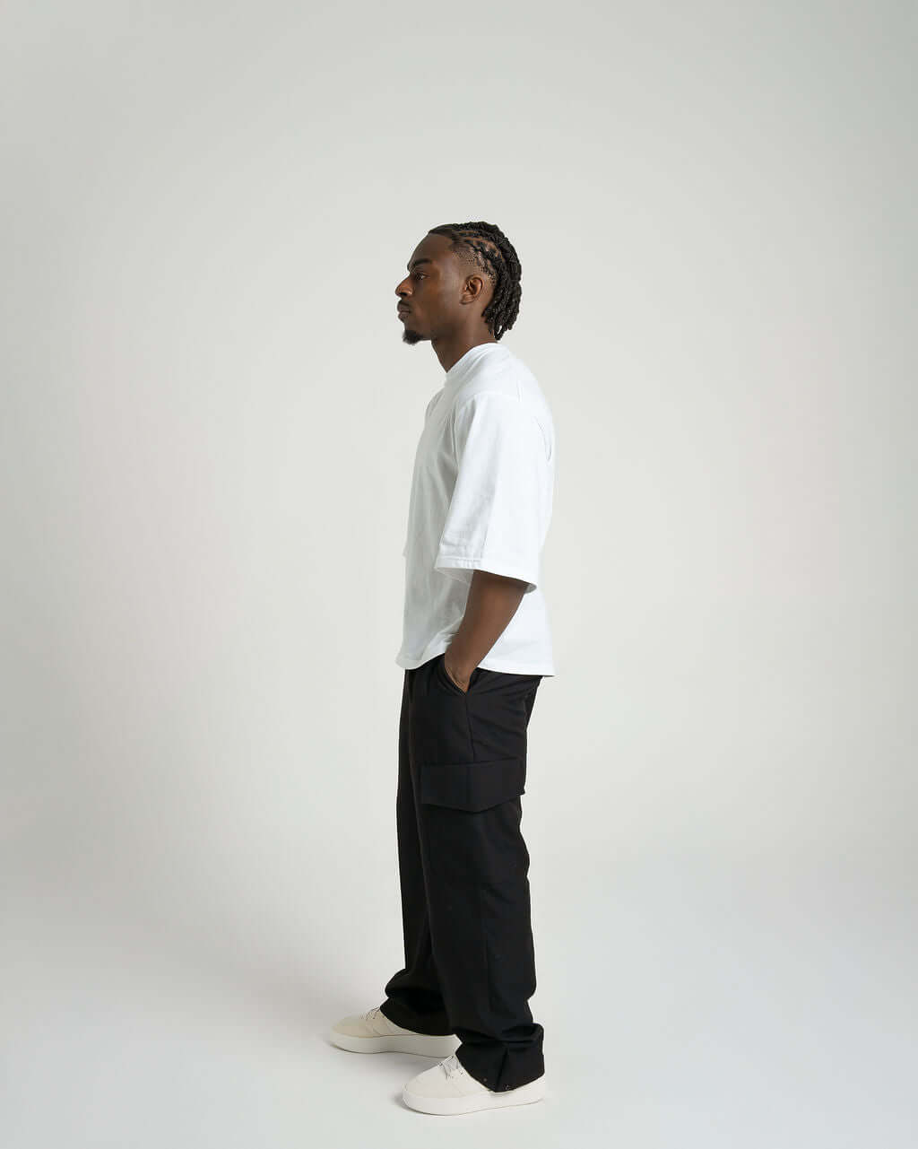 Model showcasing tailored black wool cargo trousers with relaxed fit and envelope pockets, styled with a white tee.