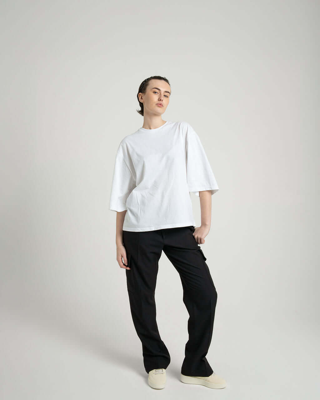 Model wearing a boxy cropped white cotton tee with slightly lengthened arms paired with black pants, showcasing comfort and style.