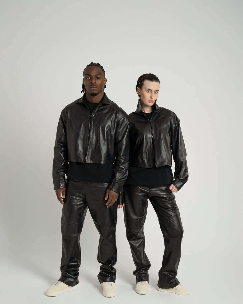 Modeling a cropped zipped black leather jacket, featuring twisted seams and a boxy fit for a stylish look.