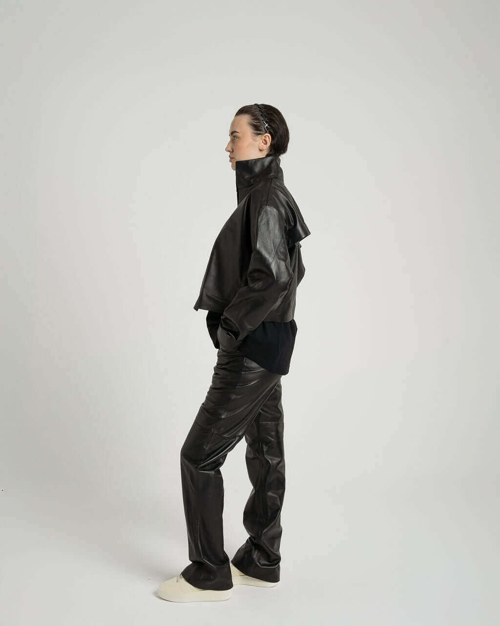 Model wearing a cropped zipped black leather jacket and matching pants, showcasing a stylish boxy fit and unique design.