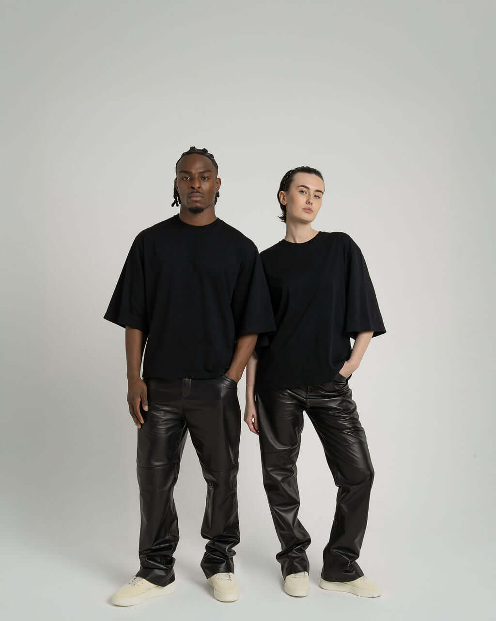 Man and woman wearing black boxy cropped tees with sleek black trousers, showcasing casual and stylish outfits.