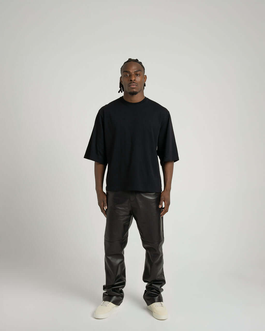 Model wearing a black boxy cropped tee paired with black leather pants, showcasing a stylish streetwear look.