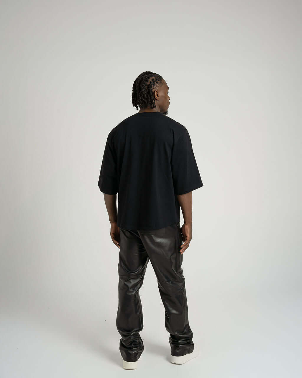 Back view of a model wearing a boxy cropped black tee with relaxed fit pants, showcasing comfort and style.