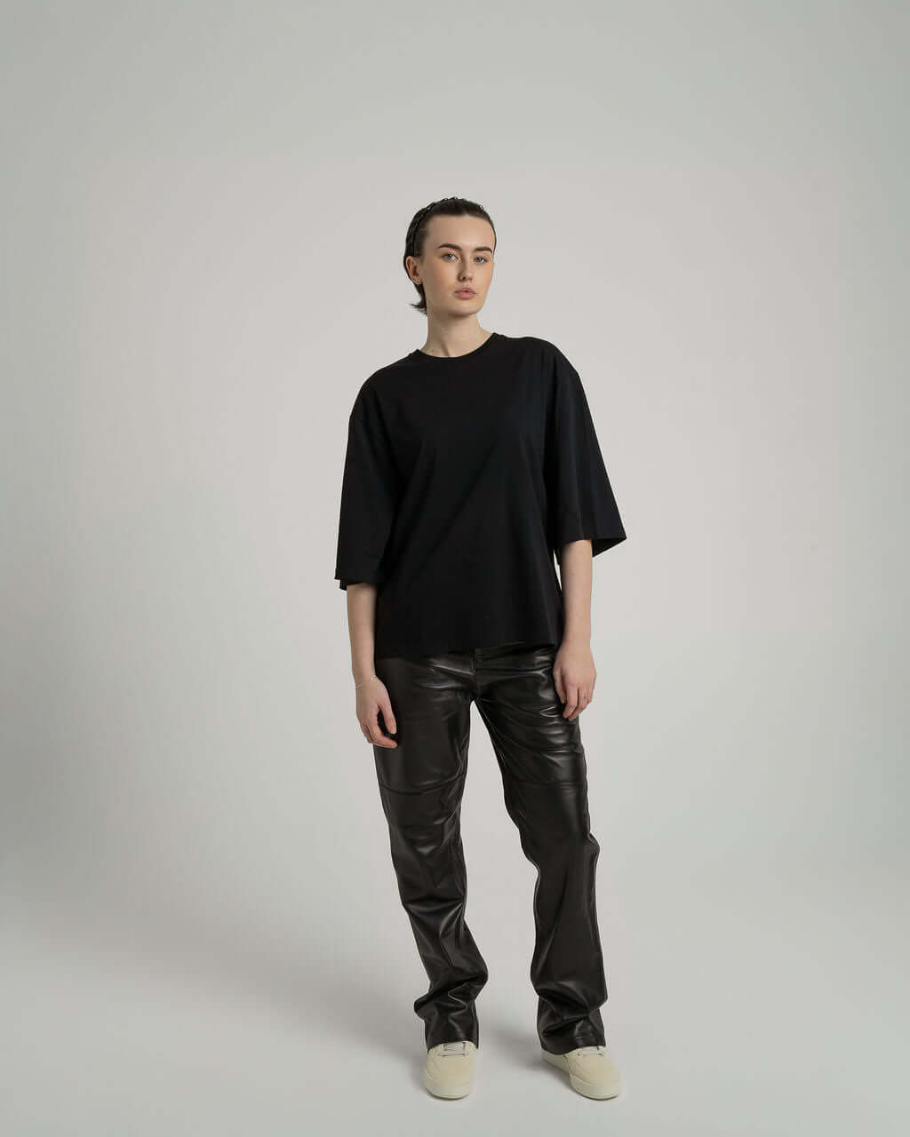 Model wearing a black boxy cropped tee with slightly lengthened arms paired with black pants, showcasing relaxed fit.