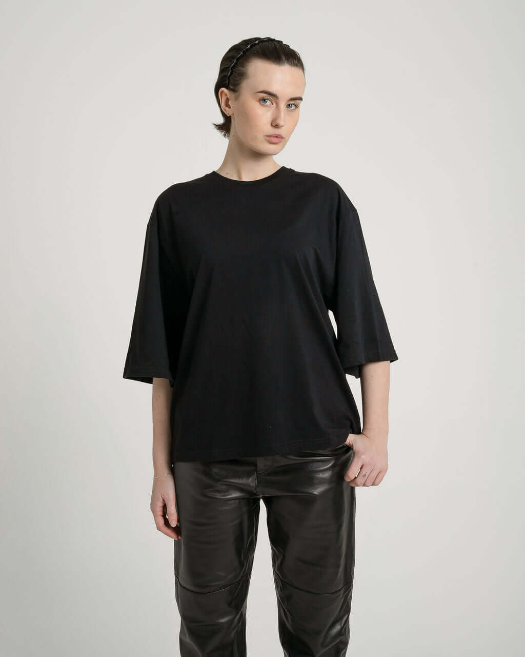 Boxy cropped black cotton tee with relaxed fit and slightly lengthened arms, model wearing size medium.