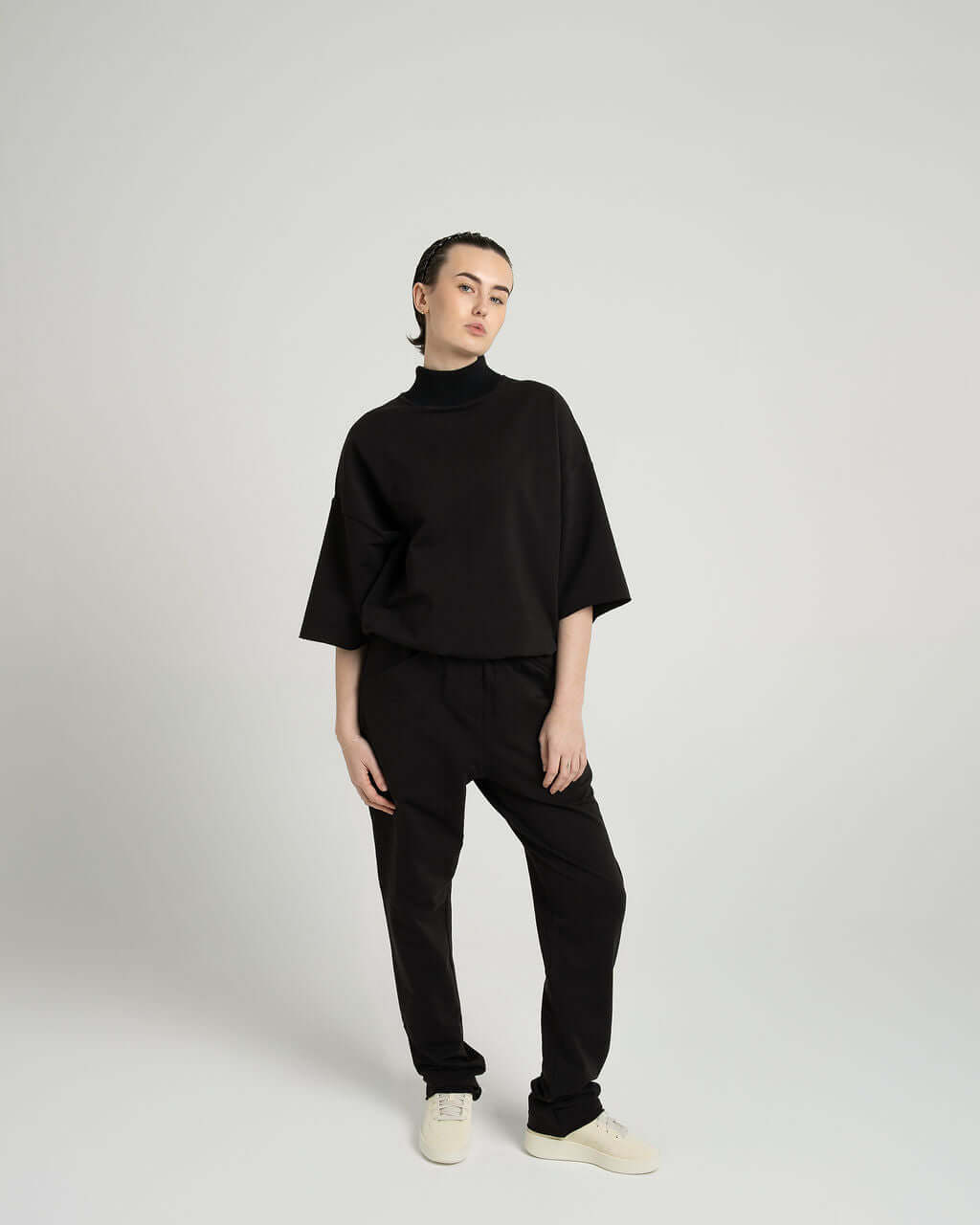 Model wearing a black 3/4 sleeve mock neck terry sweatshirt paired with relaxed pants, showcasing an oversized fit.