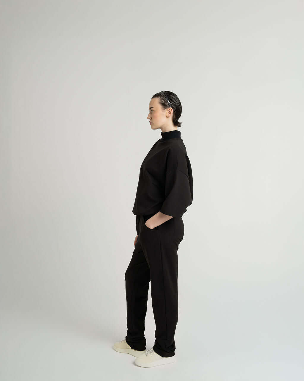 Model wearing a black 3/4 sleeve mock neck terry sweatshirt, showcasing an oversized fit and minimalist style.
