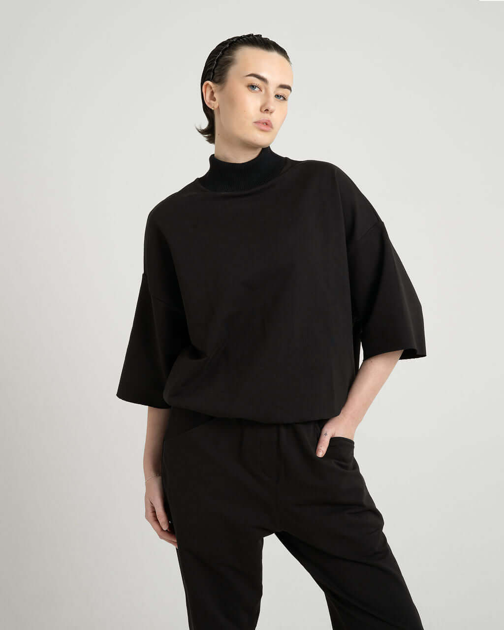 Model wearing a black 3/4 sleeve mock neck terry sweatshirt featuring an oversized fit and soft ribbed details.