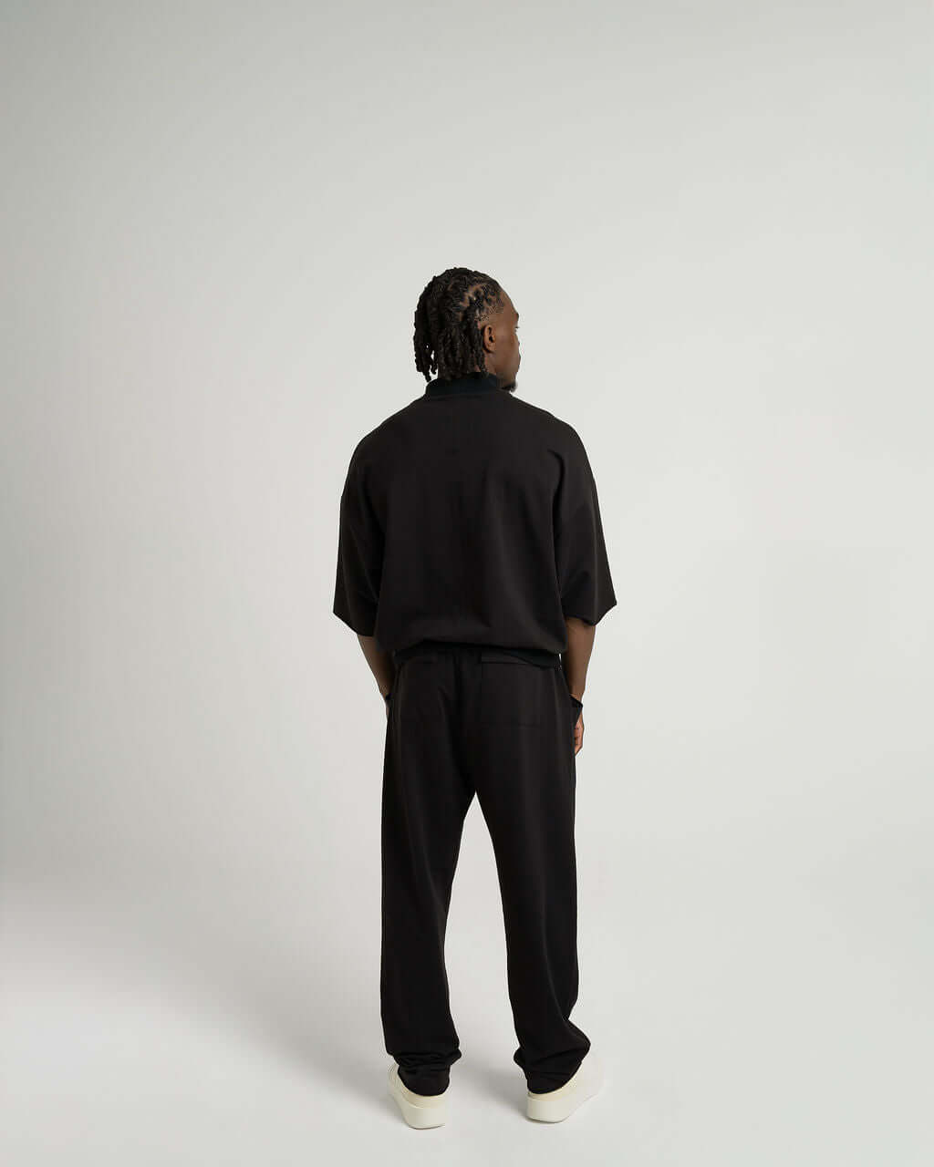 Model wearing a black 3/4 sleeve mock neck terry sweatshirt from the back, showcasing an oversized fit.