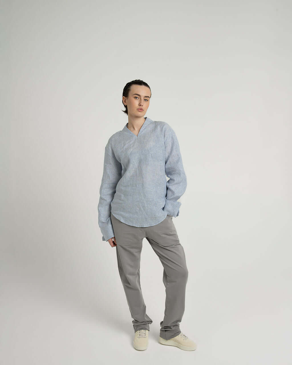 Blue and white striped linen long sleeve shirt with v-neck, styled with relaxed fit and grey pants.