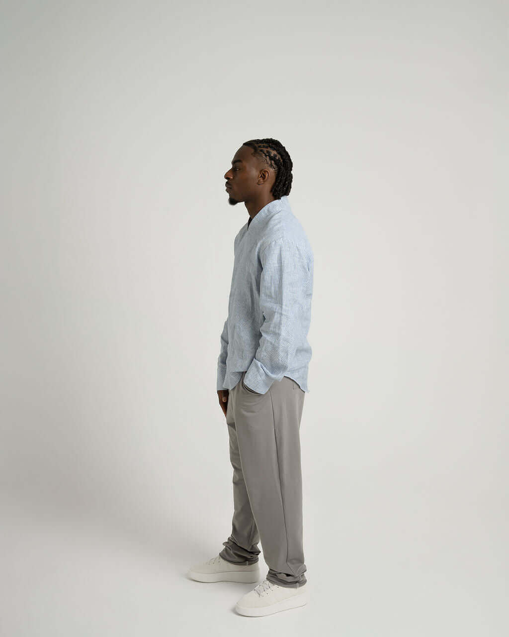 Model wearing a blue and white striped linen long sleeve pull over shirt with v-neck and relaxed fit.