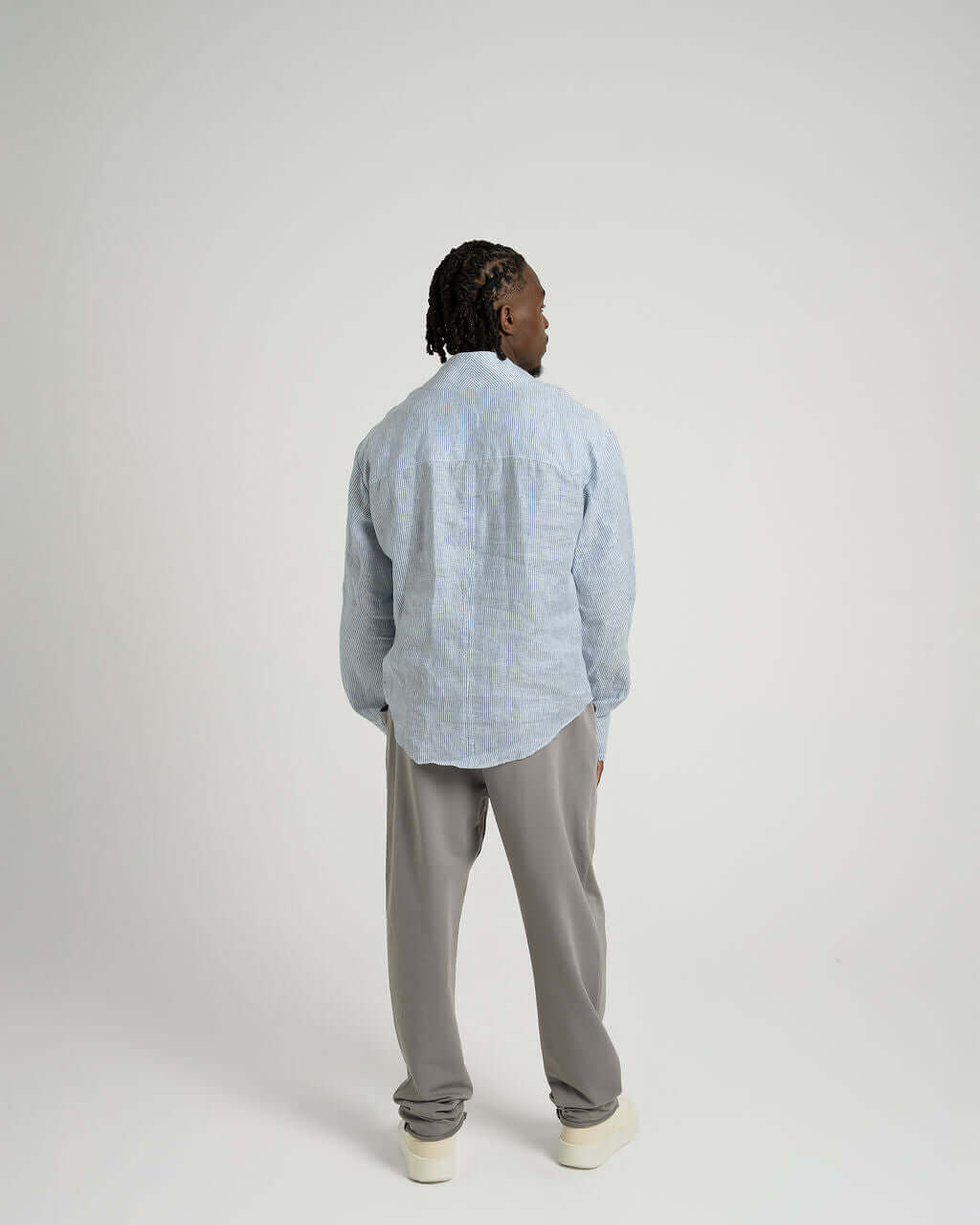 Blue and white striped linen long sleeve shirt with v-neck, view from the back on model wearing relaxed fit.