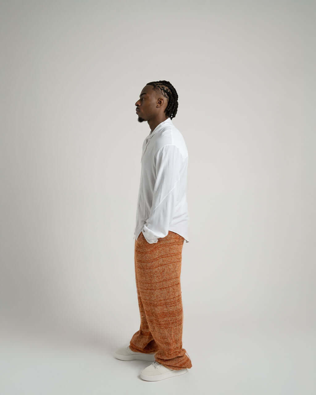 Model in relaxed fit white viscose shirt with neck tie collar, styled with orange pants.