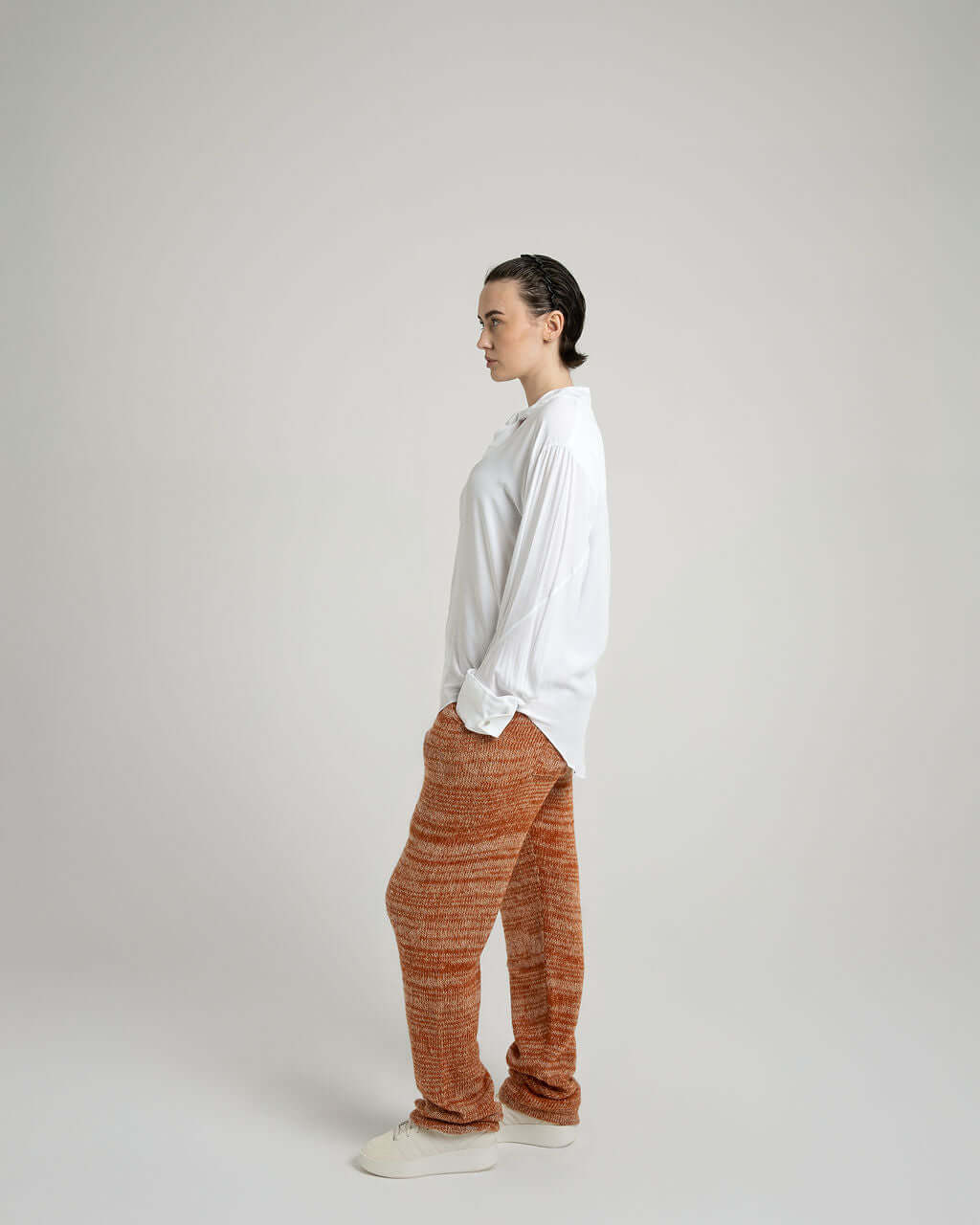 Model wearing a white viscose shirt with neck tie collar and orange patterned joggers, showcasing relaxed style.