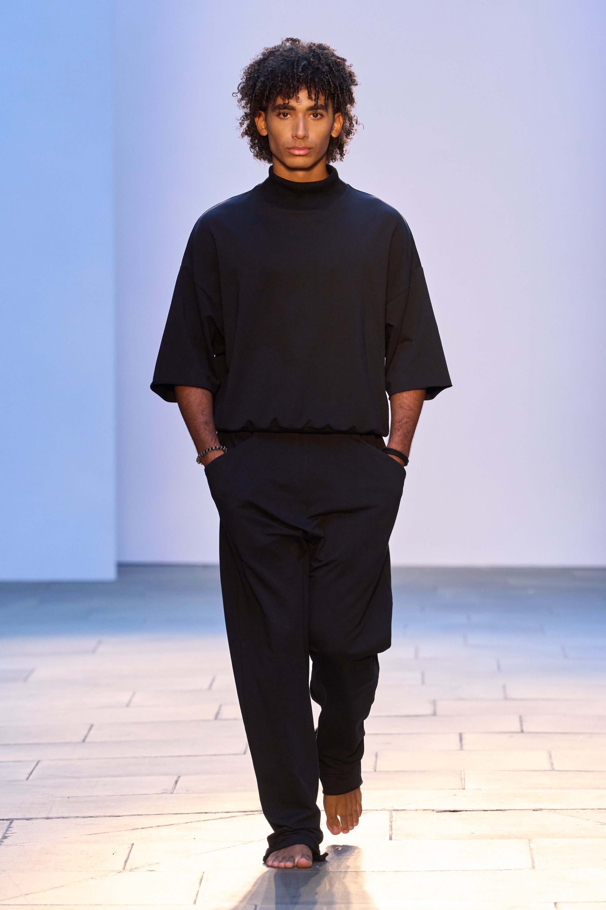 Model wearing a black 3/4 sleeve mock neck terry sweatshirt with relaxed fit and matching pants.
